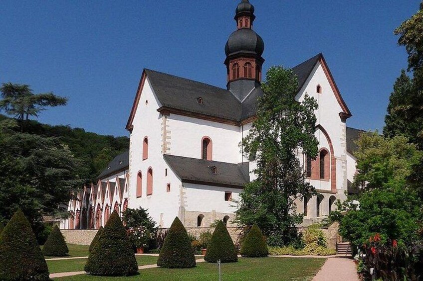 A large white church with a bell tower, surrounded by well-manicured gardens and trees. 3