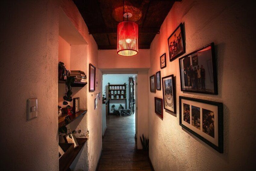 A hallway with a wooden floor, a red hanging light, and framed pictures on the walls. 5