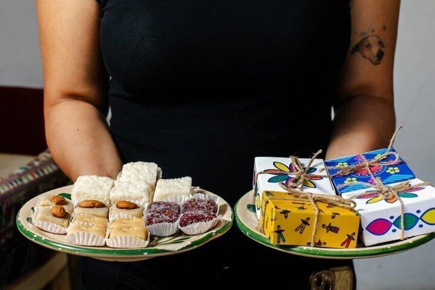 A person holding two trays of assorted sweets and gift boxes. 4