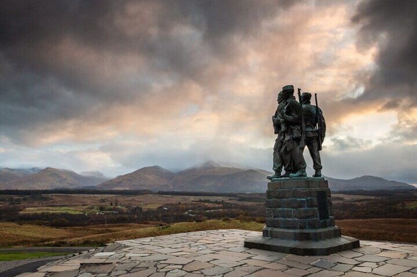 A statue of two soldiers on a pedestal with a mountainous landscape in the background. 4