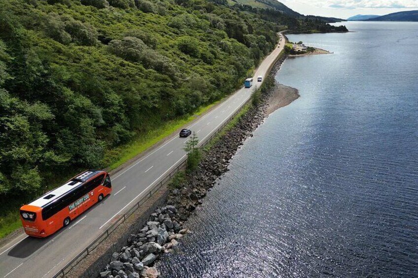 A road alongside a body of water with a bus and a car. 1