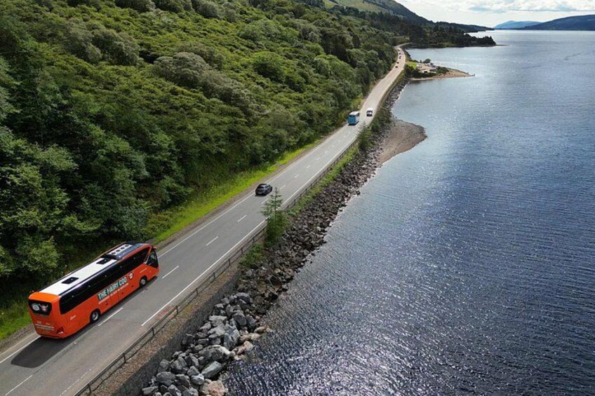 A road alongside a body of water with a bus and a car. 1