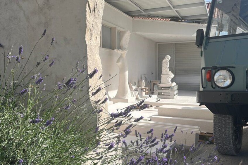 A vehicle parked in front of a house with white statues and lavender plants. 4