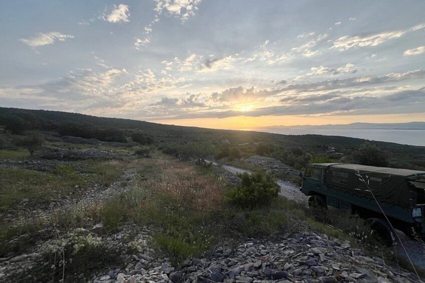 A jeep on a rocky path with a sunset in the background. 2