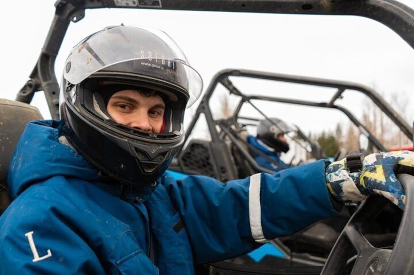 A person in a blue jacket and helmet inside a vehicle. 3