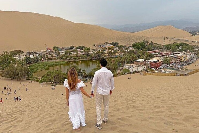 A couple walking on a sandy beach with a cityscape in the background. 3