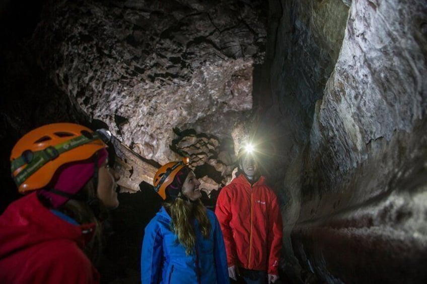 A group of people inside a cave with a flashlight illuminating the area. 1