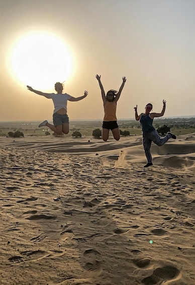 Three people jumping in a desert landscape with a sunset in the background. 5