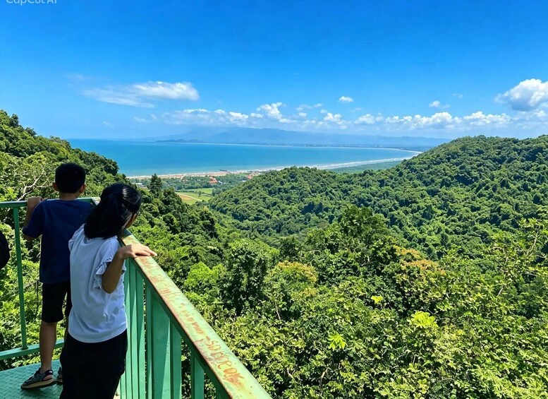 Two people overlooking a coastal landscape from a green observation deck. 1