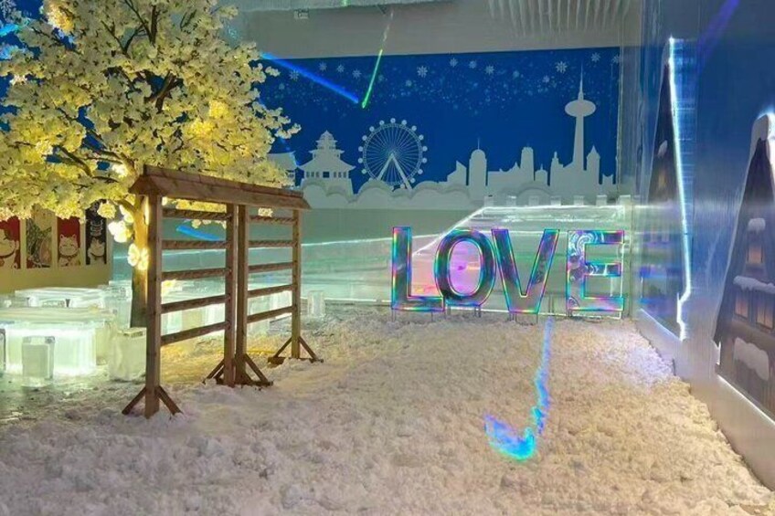 A snowy scene with a wooden structure, a tree, and the word 'LOVE' illuminated in the background. 3