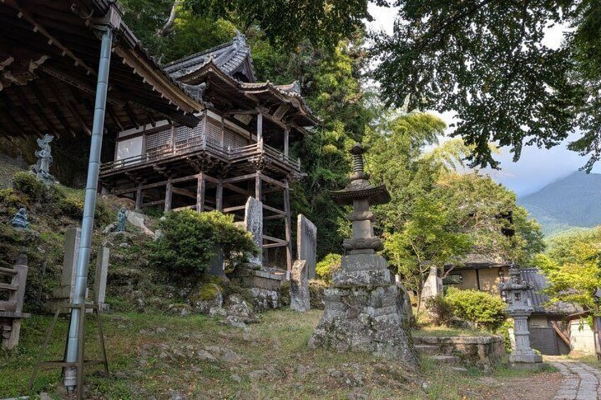 A traditional Japanese temple with a multi-tiered pagoda, stone lanterns, and lush greenery. 5