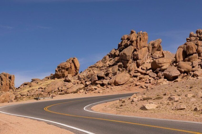 A winding road through a rocky desert landscape with large boulders. 5