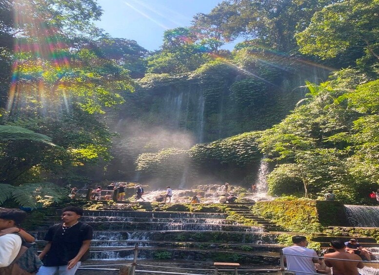 A waterfall cascading down a series of steps surrounded by lush greenery. 2
