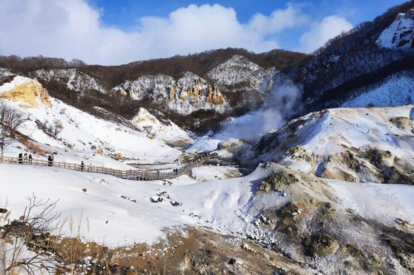 A snow-covered mountainous landscape with a wooden fence and a steam vent. 3