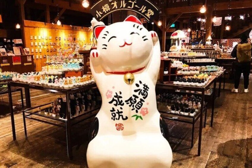 A shop interior with a large cat statue, wooden shelves, and various items on display. 4