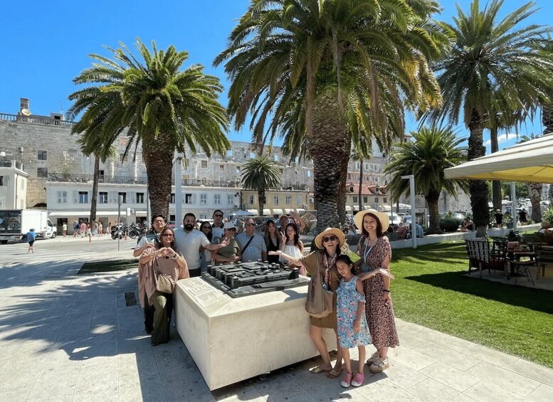 A group of people posing in a public square with palm trees and historic buildings in the background. 4