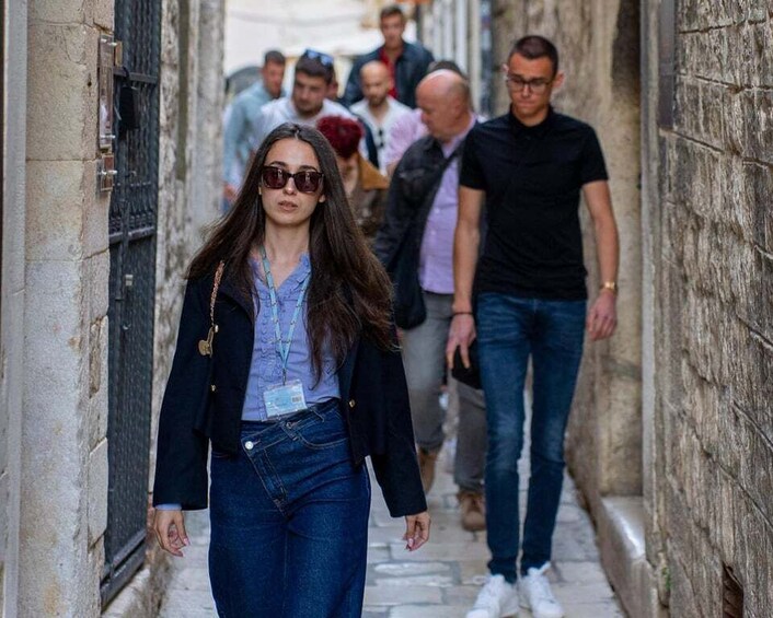 A person walking down a narrow street with stone walls and a metal gate. 5