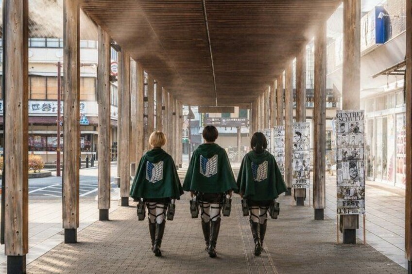 Three people walking down a covered walkway with posters on the sides. 1