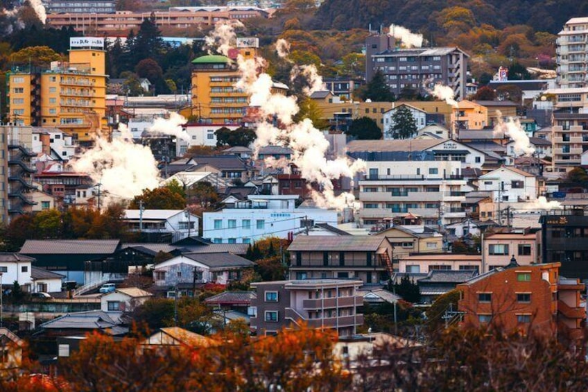 A cityscape with multiple buildings and smoke stacks emitting smoke. 2