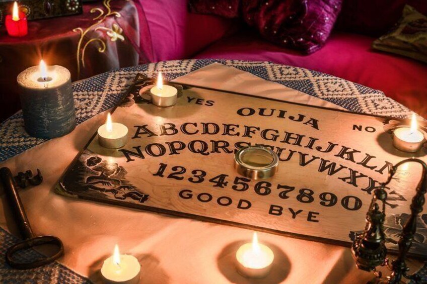 A Ouija board with candles and a crystal ball on a table. 2