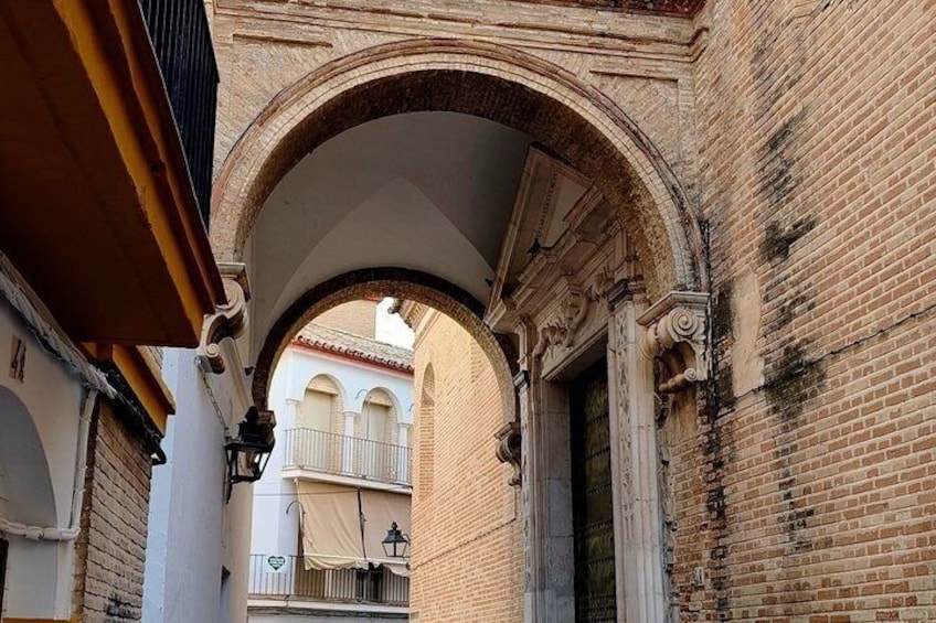 An arched passageway with brick walls and a balcony in the background. 3