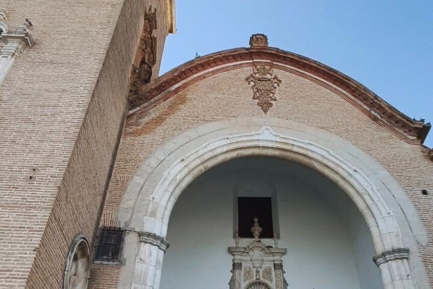 A brick building with a large arched entrance and a decorative crest above it. 4