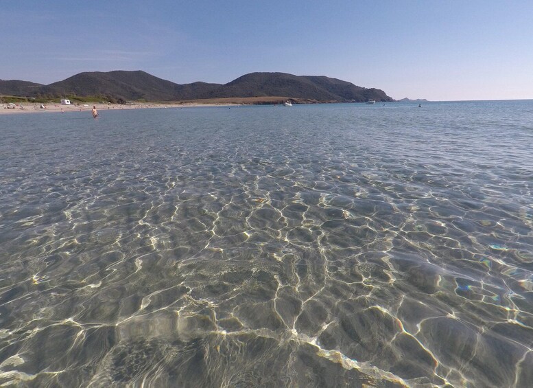 Clear shallow water, a sandy beach, and distant mountains. 5