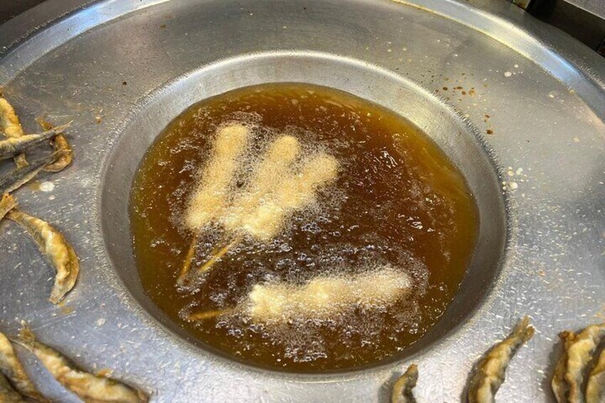 A frying pan with oil and food items being cooked. 4