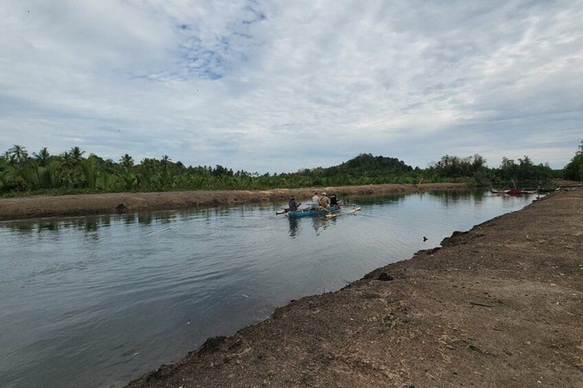 A calm river with a boat carrying people, surrounded by greenery and a clear sky. 5