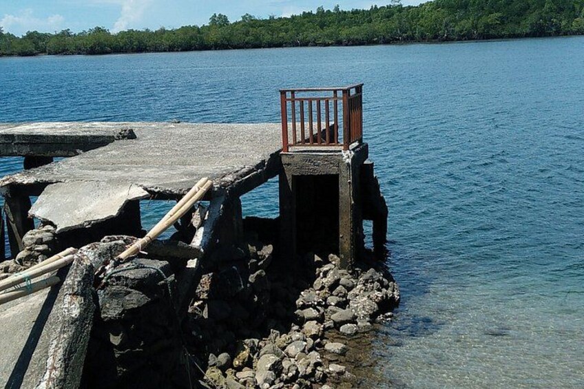 A wooden pier extending into a calm lake, surrounded by rocks and vegetation. 4