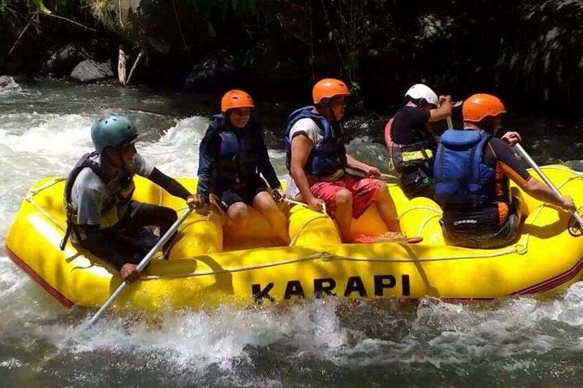 A group of people rafting on a yellow inflatable raft labeled 'KARAPI' on a river. 3