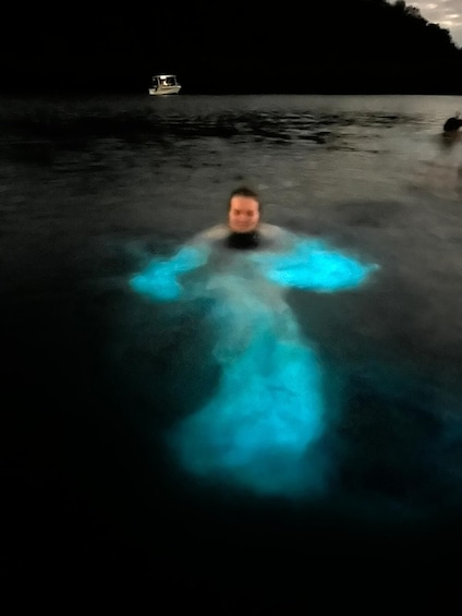 A person in a body of water with a boat in the background. 1