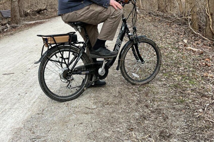 A person riding a mountain bike on a dirt path with a basket attached to the rear. 3