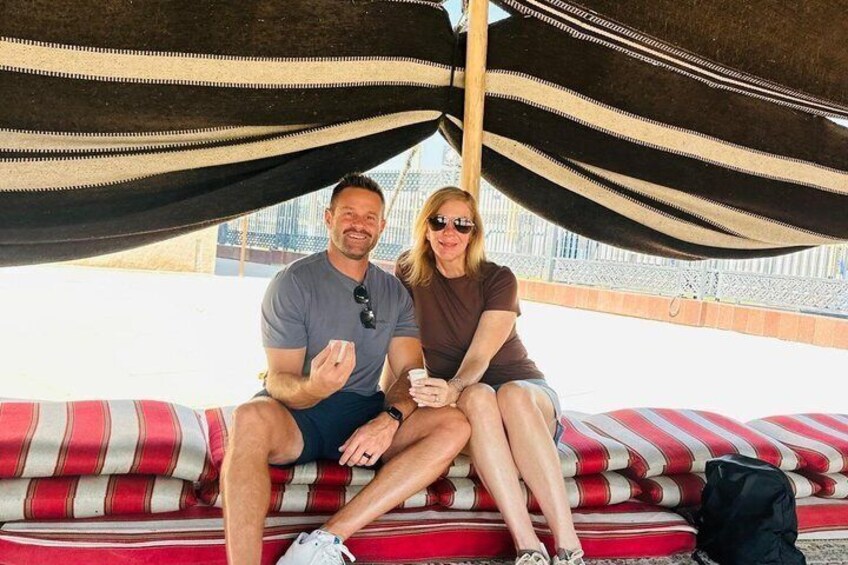 Two people sitting on a striped couch under a striped canopy. 1