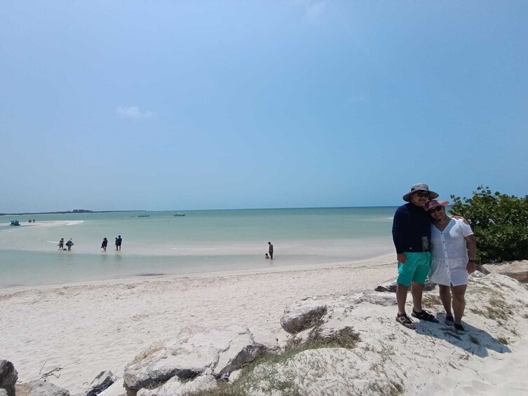 A beach with people walking and standing on the sand, a clear sky, and calm sea. 5