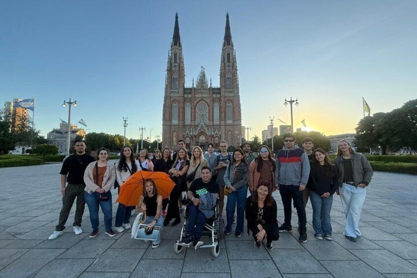 A group of people posing in front of a large cathedral with two tall spires. 4