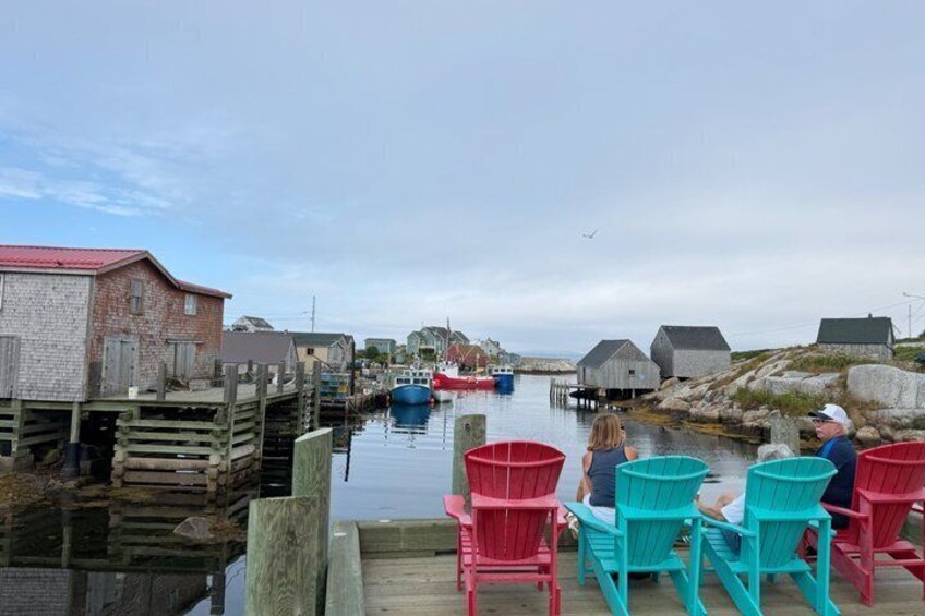 A waterfront scene with wooden docks, boats, and colorful Adirondack chairs. 3