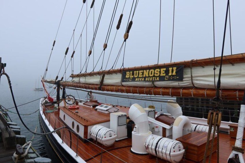 A ship's deck with a sign reading 'BLUENOSE II NOVA SCOTIA,' a steering wheel, and life preservers. 1