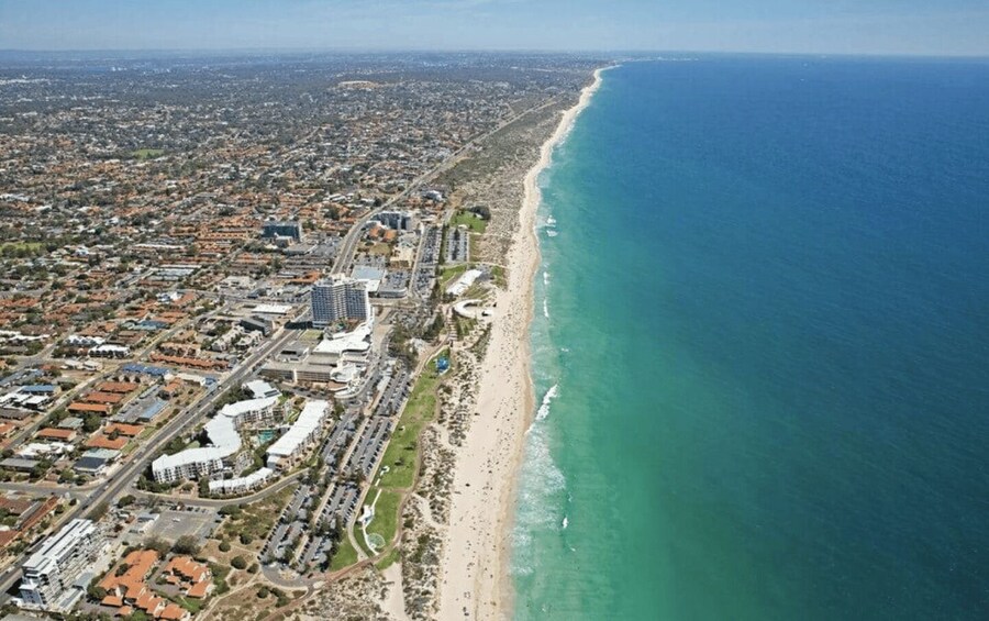 An aerial view of a coastal city with a long beach, dense urban area, and clear blue ocean. 5