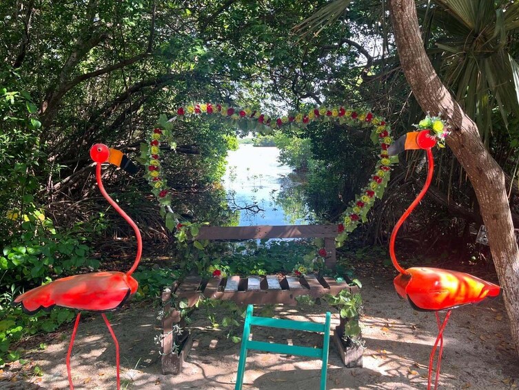 Puinen penkki, jossa on sydämenmuotoinen kukka-arkadi ja kaksi flamingo-patsasta. 4