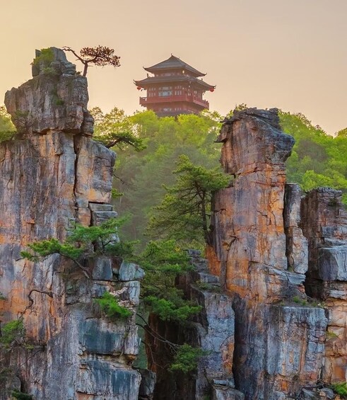 A traditional Chinese pagoda on a hill, surrounded by rocky cliffs and lush greenery. 3