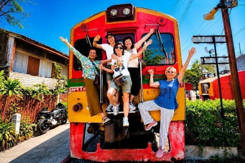 A group of people posing on a stationary train with a red and yellow color scheme. 3