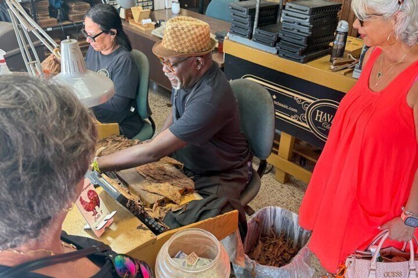 A person seated at a table with a box of items, possibly food, in front of them. 1