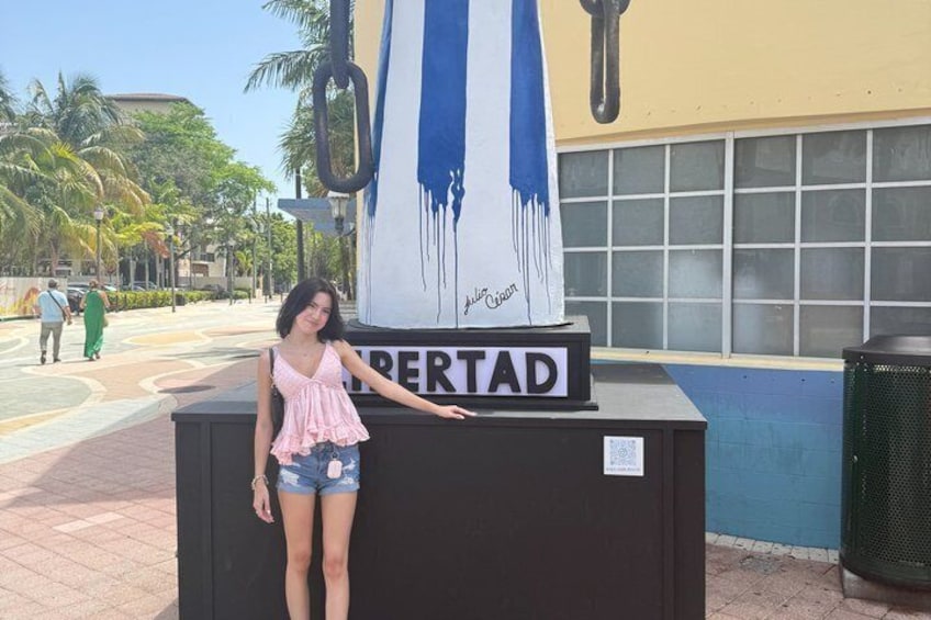 A person standing in front of a sign that reads 'LIBERTAD' with a blue and white striped flag above it. 3