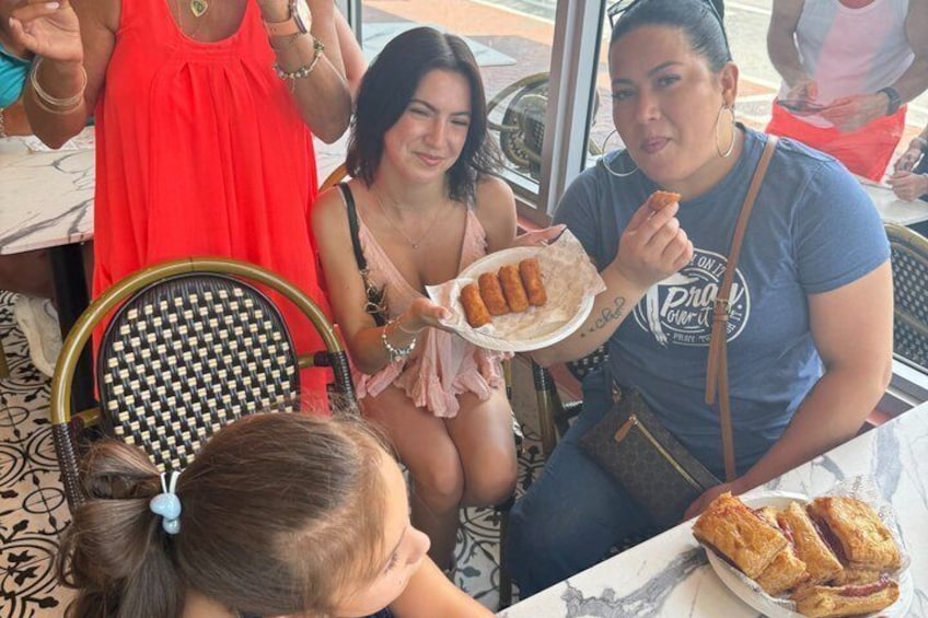 People sitting at a table with food, including a plate with what appears to be tacos and a basket with pastries. 5