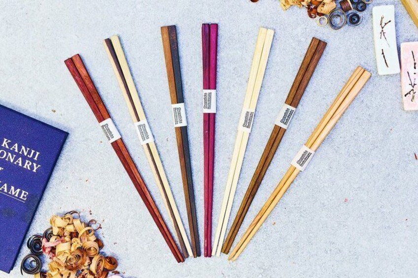 A variety of chopsticks, some with labels, on a textured surface. 2