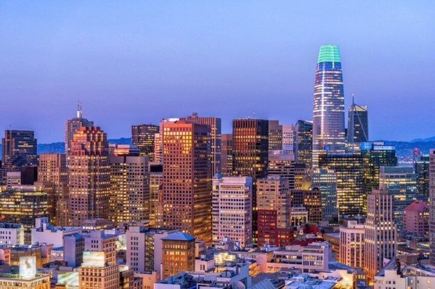 A city skyline at dusk with illuminated buildings and a prominent skyscraper. 4