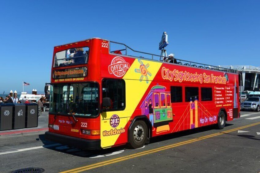 A double-decker bus with colorful graphics and text advertising a city sightseeing tour. 1