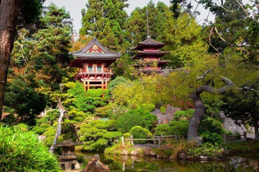 A traditional Japanese pagoda surrounded by lush greenery and a calm pond. 2
