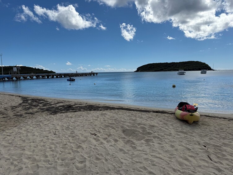 A beach with a kayak, a pier, and boats in the water. 2